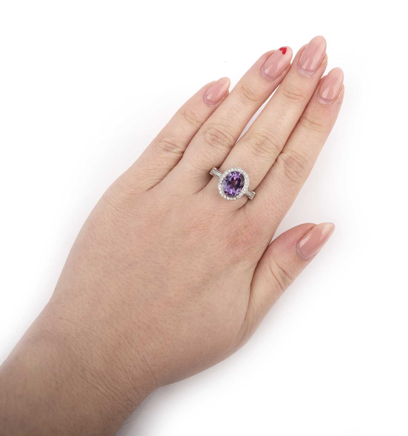 An amethyst and diamond cluster ring, the oval amethyst set within a surround of circular-cut - Image 2 of 2