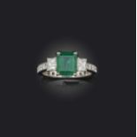 An emerald and diamond ring, claw-set with a step-cut emerald weighing approximately 1.60 carats,