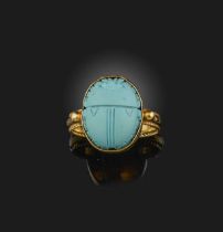 A gold and reconstituted turquoise ring, designed in the Egyptian revival style, set with a carved