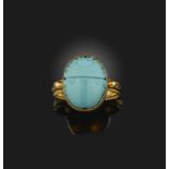 A gold and reconstituted turquoise ring, designed in the Egyptian revival style, set with a carved