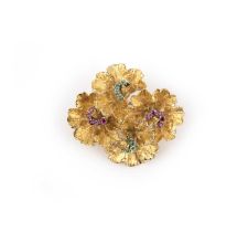 A gold, emerald and ruby brooch, Italy, 1970s, designed as four abstract flowers in textured gold,
