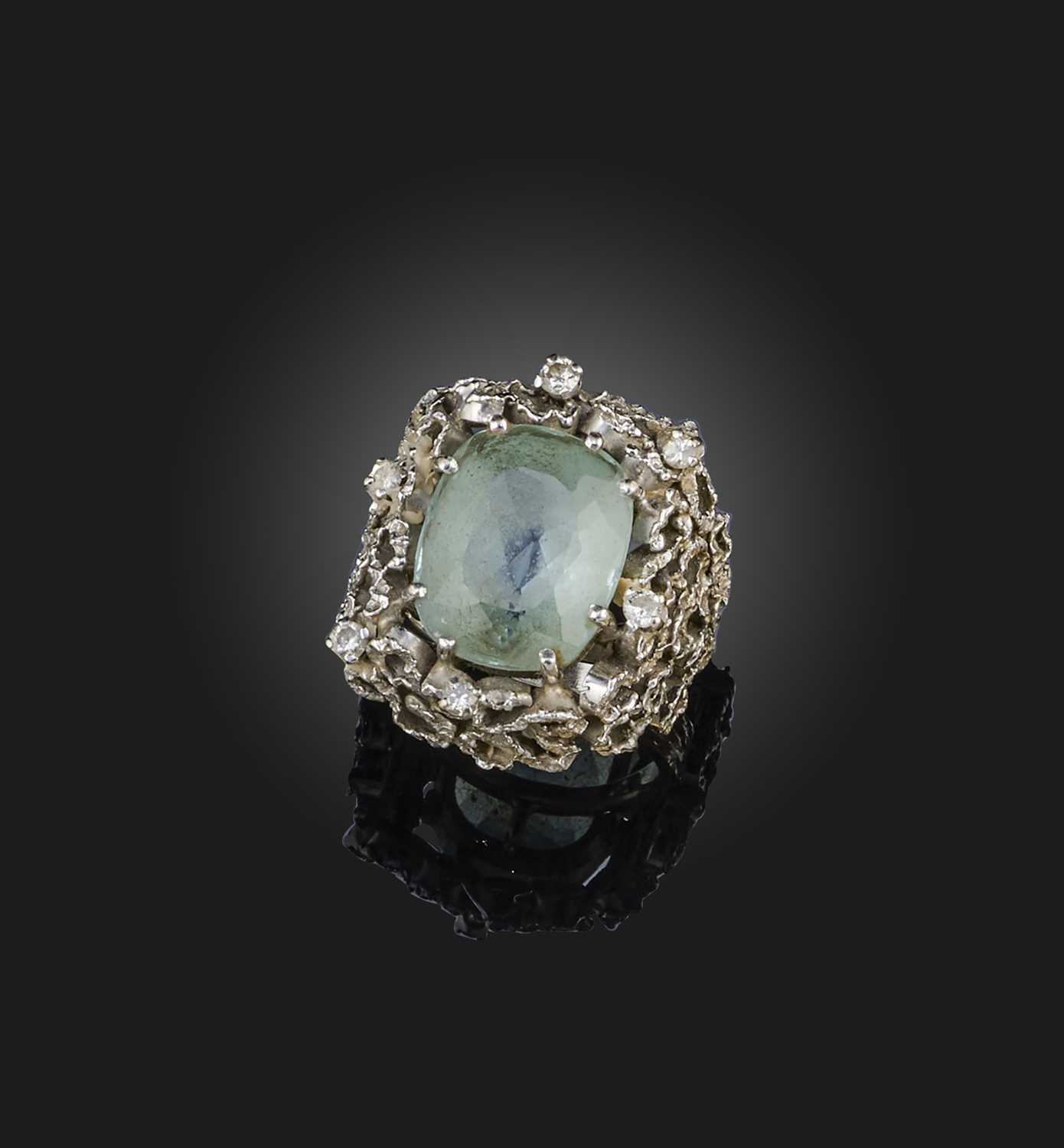 An aquamarine & diamond ring, 1970s, set with a cushion-shaped aquamarine, within an abstract