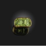 A peridot ring, channel-set with a square step-cut peridot between two demi-lune peridots, mounted