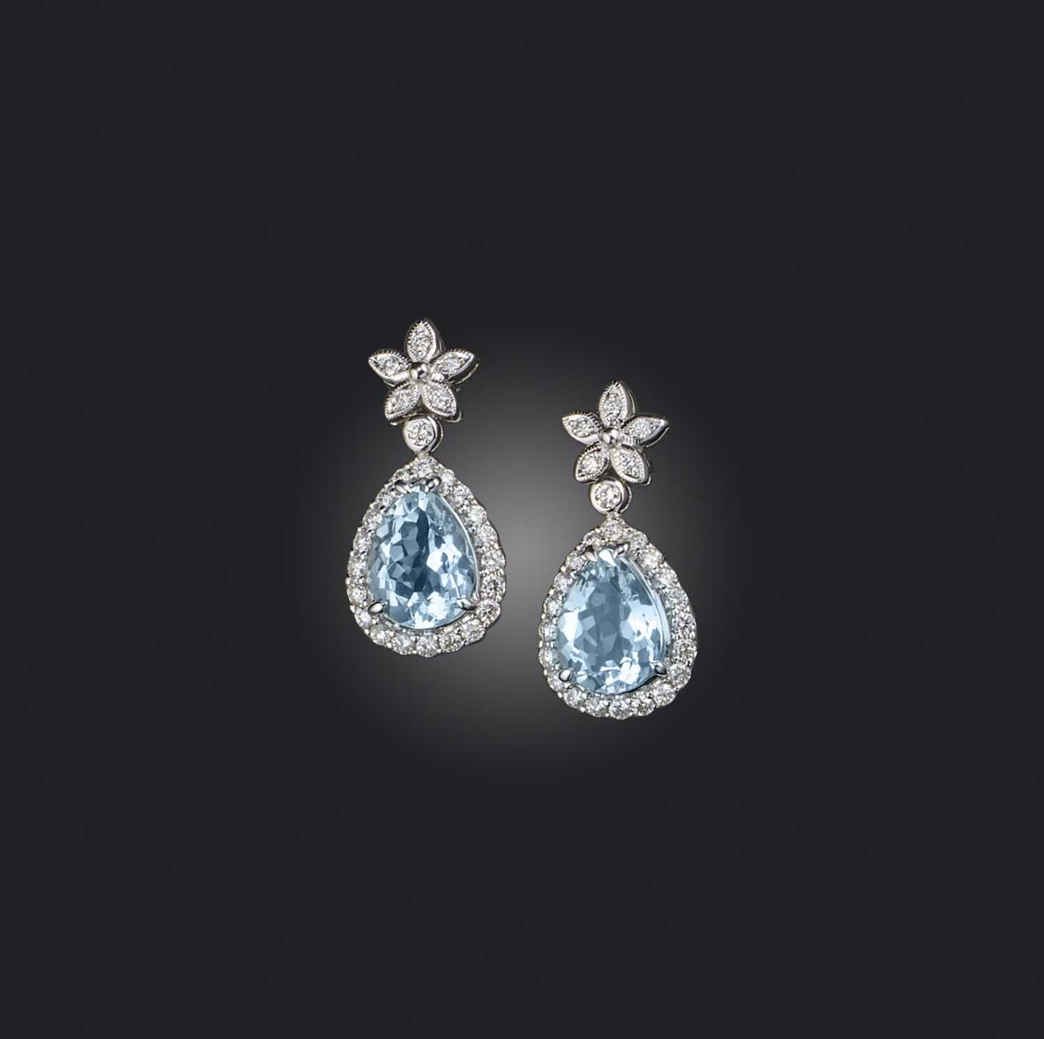 A pair of aquamarine and diamond earrings, each of drop design, composed of a floral surmount