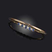 A sapphire and diamond bangle, early 20th century, centring on a line of five cabochon sapphires