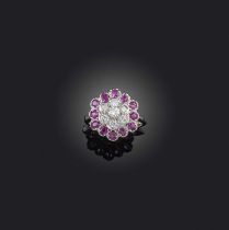 A ruby and diamond cluster ring, set with circular-cut diamonds within a border of rubies in white