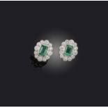 A pair of emerald and diamond earrings, of cluster design, set with step-cut emeralds totalling 1.10