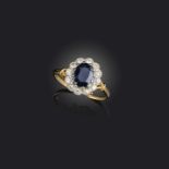 A sapphire and diamond cluster ring, the oval-shaped sapphire set within a surround of circular-