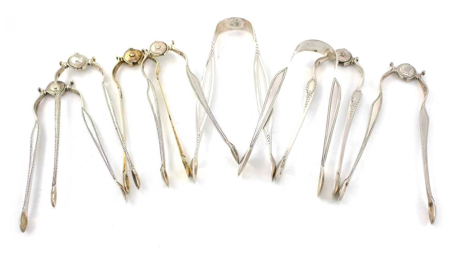 A collection of eight pairs of George III silver sugar tongs, various dates and makers, including: