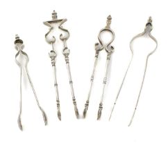A collection of four pairs of early-18th century silver sugar tongs, comprising: an andiron pair,