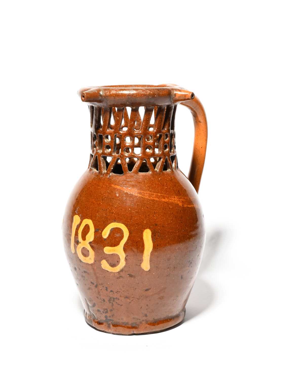 A large slipware puzzle jug, dated 1831, inscribed 'J + ny 1831' in cream slip on a rich treacle