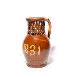 A large slipware puzzle jug, dated 1831, inscribed 'J + ny 1831' in cream slip on a rich treacle