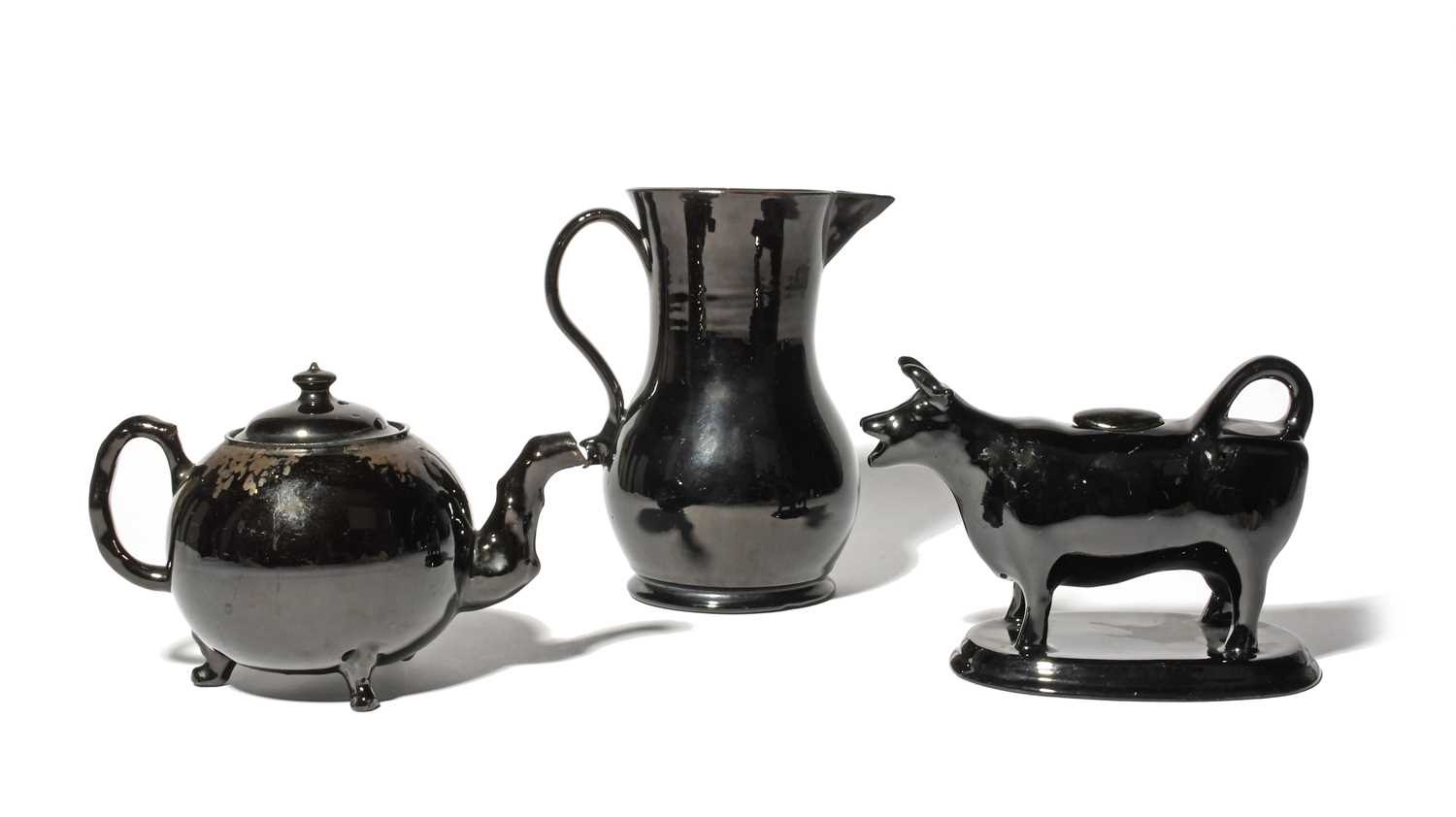 A large Jackfield jug and a teapot and cover, c.1760-80, the teapot with crabstock spout and handle,