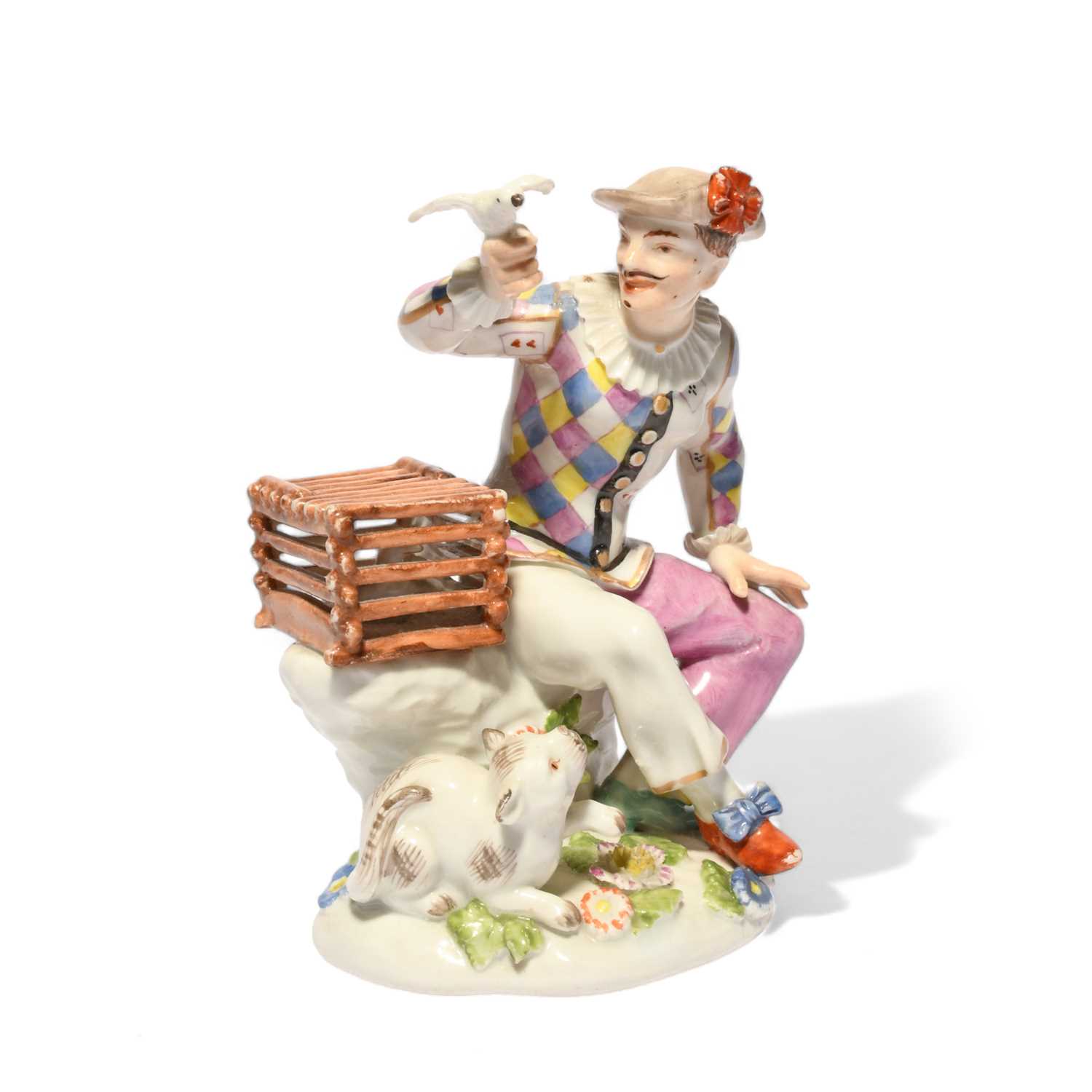 A Meissen figure of Harlequin, mid 18th century, modelled by J F Eberlein, seated and holding a bird
