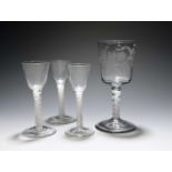 Three wine glasses and a goblet, c.1760, the wine glasses with round funnel bowls, raised on multi-