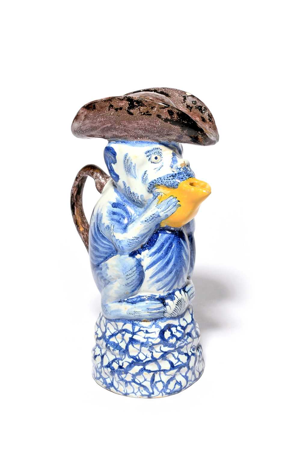 A Delft comical monkey jug and cover, mid 18th century, modelled as a monkey holding a fruit up to