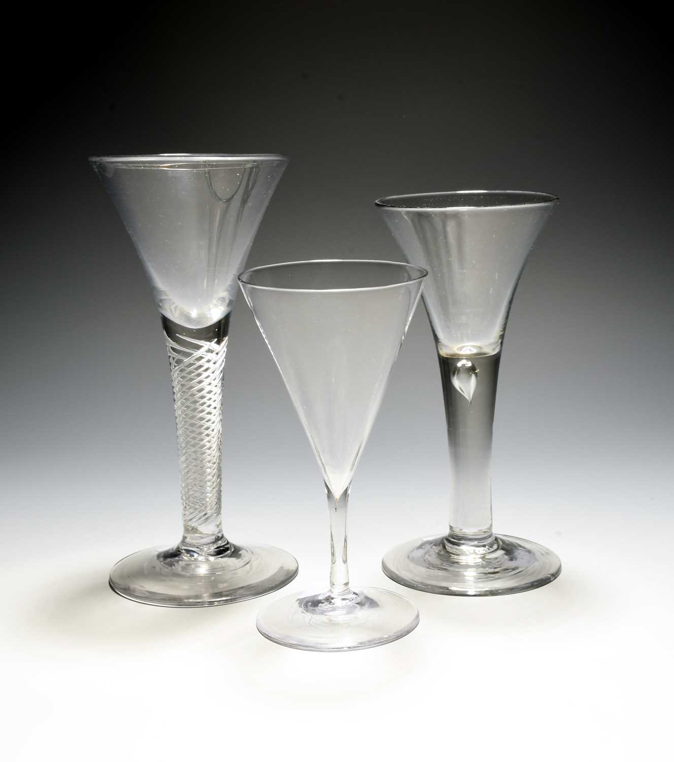 Three wine glasses, c.1750-60, with drawn trumpet bowls, one raised on a dense airtwist stem,