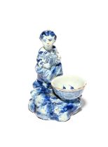 A small Delft figural salt, 18th century, modelled as a girl seated and holding a box or instrument,