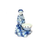 A small Delft figural salt, 18th century, modelled as a girl seated and holding a box or instrument,