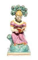 A Staffordshire figure of a girl, 1st half 19th century, seated on a rocky stump beneath flowering