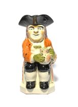 An unusual Pratt ware Toby jug, c.1800, seated with a patterned jug of ale, wearing an ochre coat