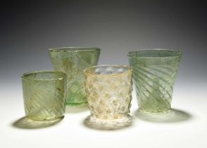 Four German waldglas beakers, 15th century, three of a pale green tone, with wrythen moulding and