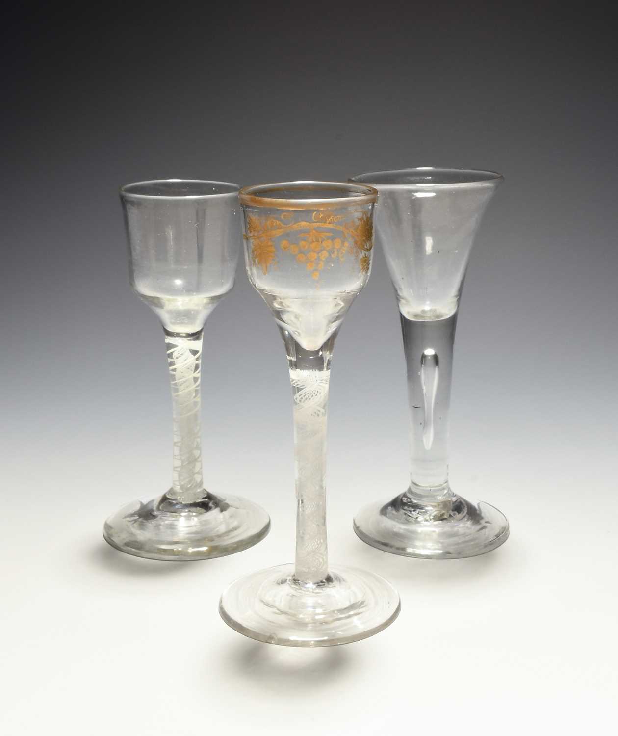 Three small wine glasses, c.1750-70, two with ogee bowls, one gilded with grapevine, both raised