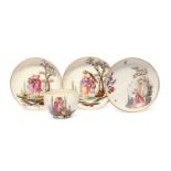A Höchst cup and two saucers, c.1780, well painted with scenes of peasants beneath fruiting trees,