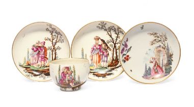 A Höchst cup and two saucers, c.1780, well painted with scenes of peasants beneath fruiting trees,