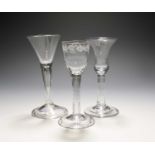 Three wine glasses, mid 18th century, one with a bell bowl on a plain stem, another a drawn