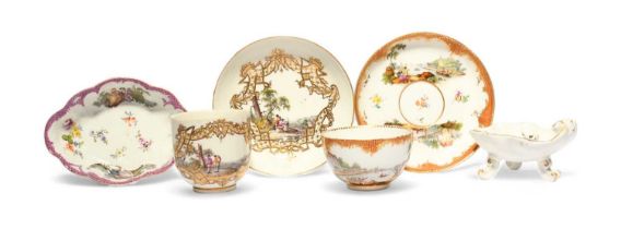 Two Meissen cups and saucers, c.1740, painted with European landscapes, one within a gilt trellis