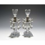 A small pair of cut glass lustre candlesticks, early 19th century, the six-petalled drip pans hung