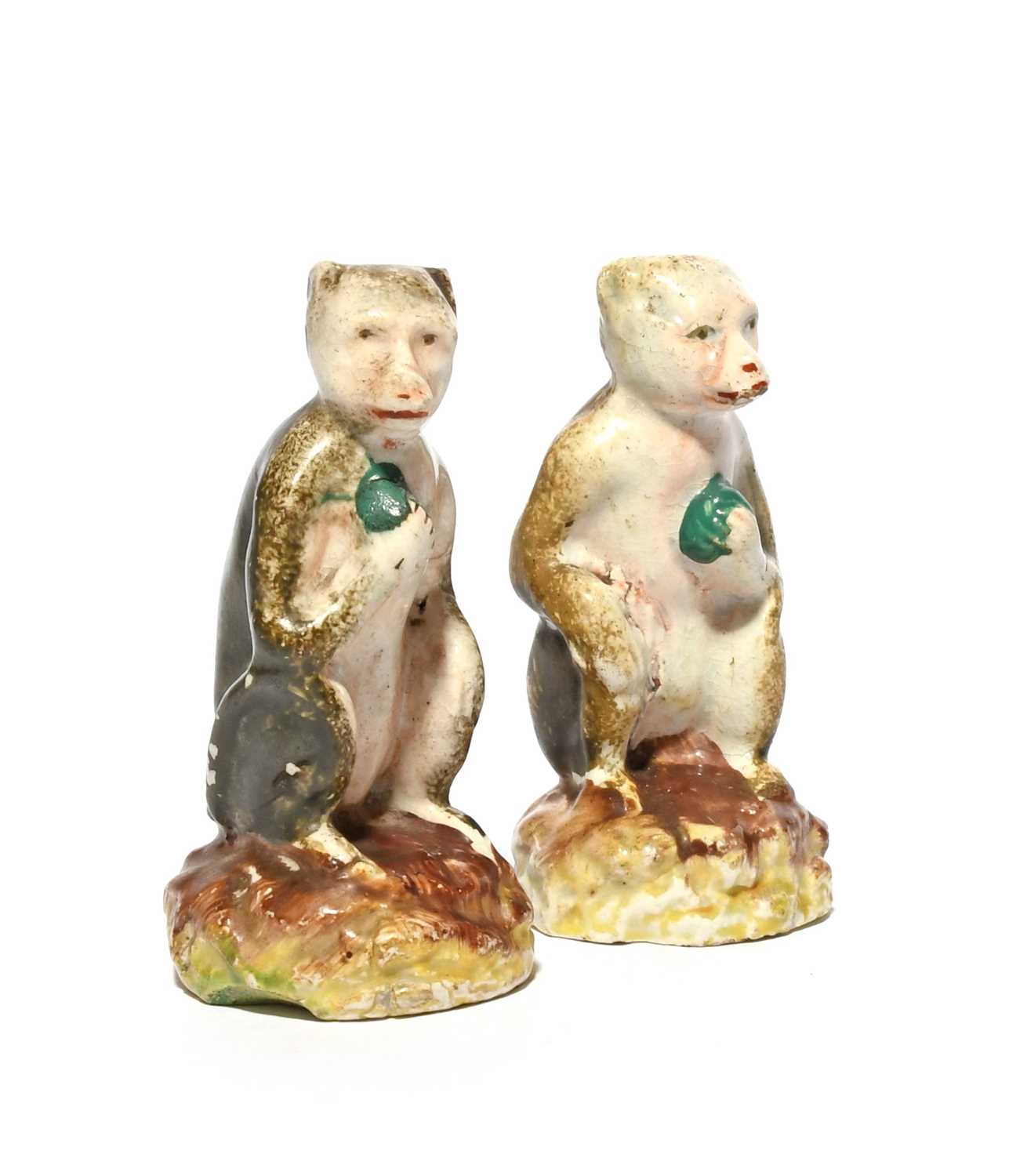 A pair of Staffordshire pearlware figures of monkeys, 19th century, each seated on a low rocky