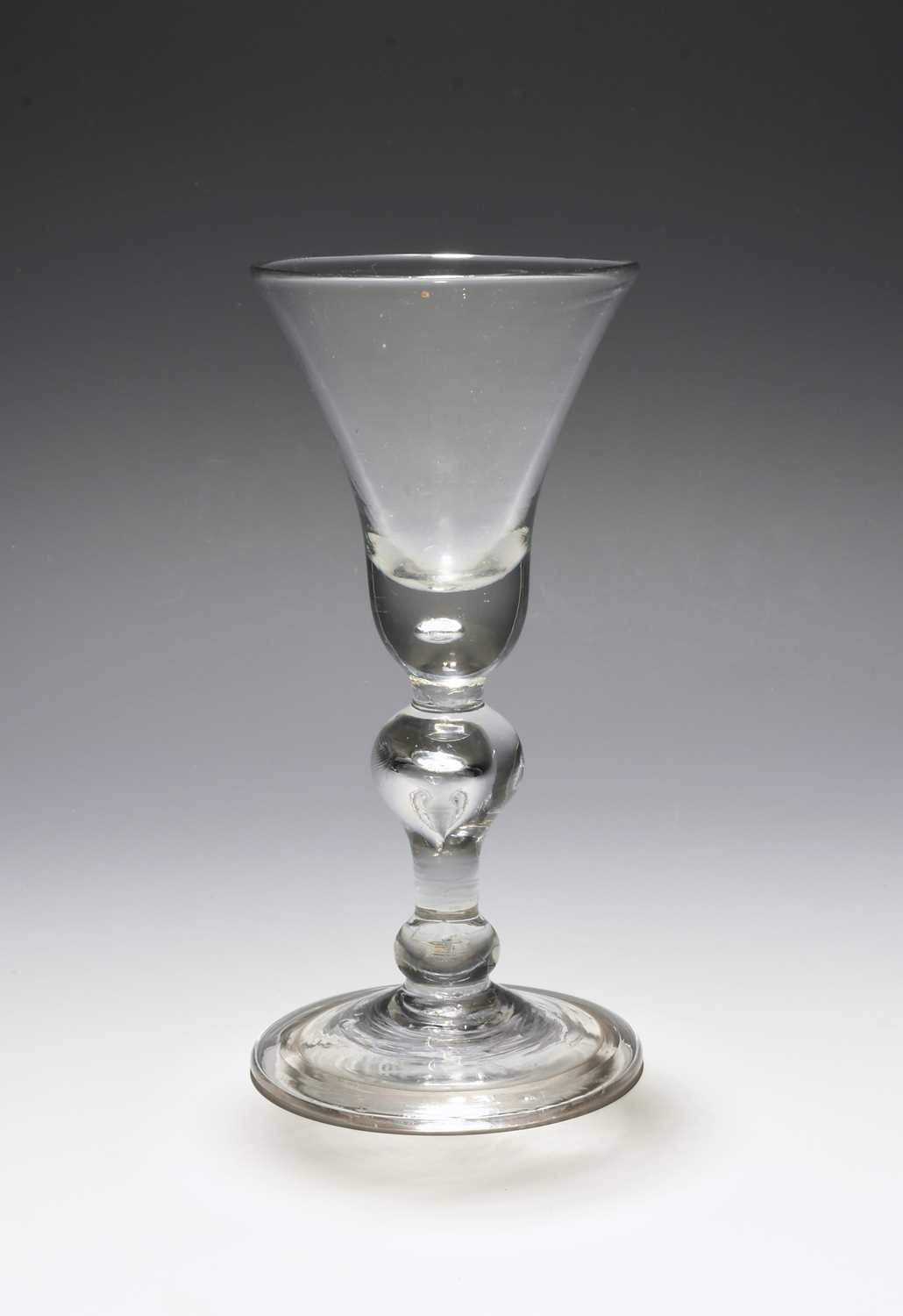 A baluster wine glass, c.1720, the bell bowl with a solid base enclosing a single tear, raised on