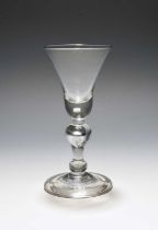 A baluster wine glass, c.1720, the bell bowl with a solid base enclosing a single tear, raised on