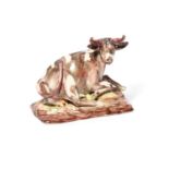 A Continental porcelain figure of a cow, late 18th century, recumbent with her left fore hoof