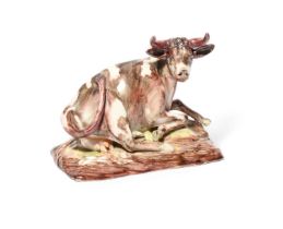 A Continental porcelain figure of a cow, late 18th century, recumbent with her left fore hoof