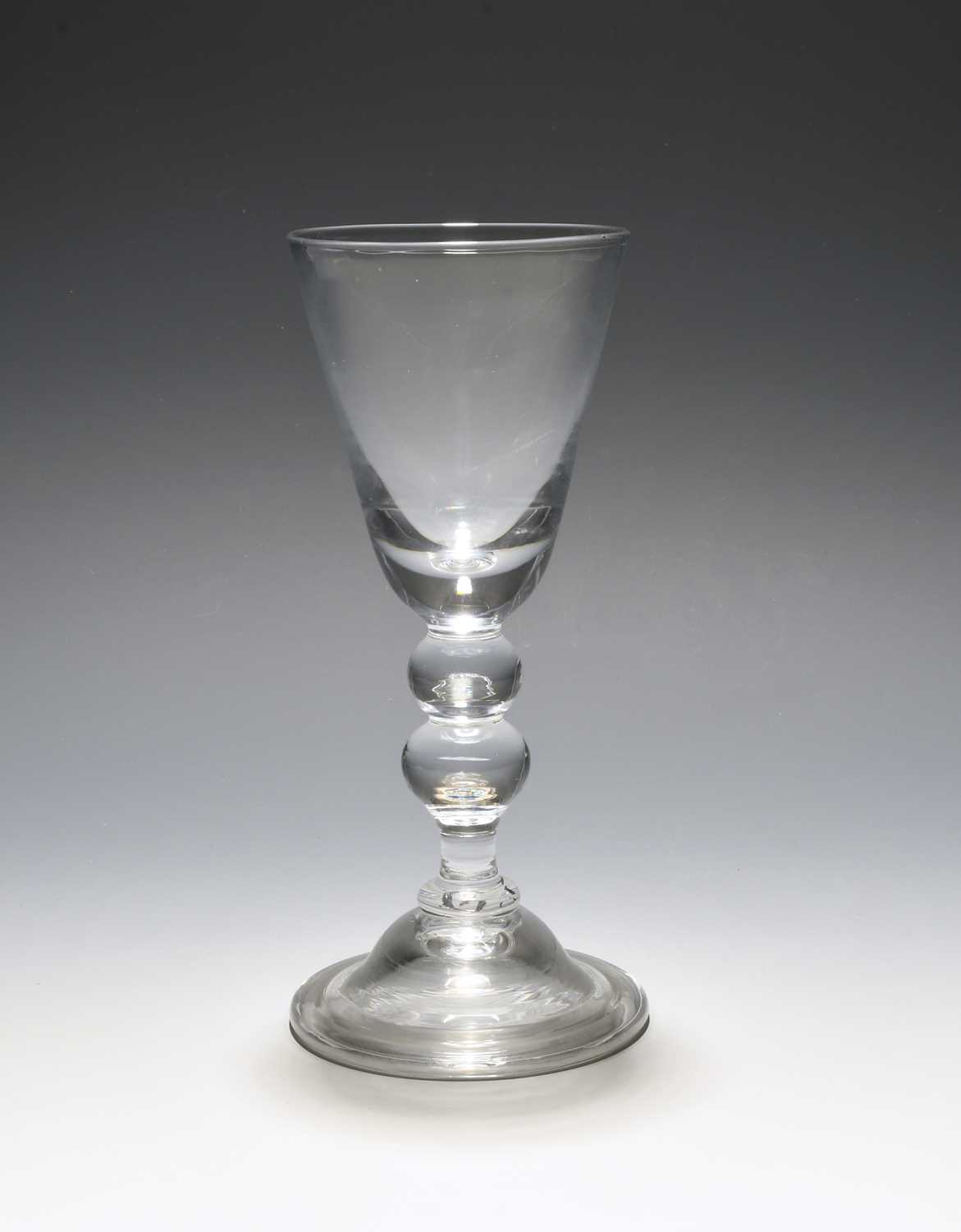 A large baluster wine glass, c.1730, the deep round funnel bowl with a solid base, raised on a