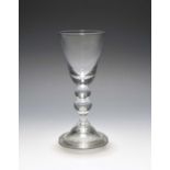 A large baluster wine glass, c.1730, the deep round funnel bowl with a solid base, raised on a
