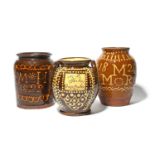 Three large slipware jars, 19th century, one decorated with a panel in cream slip inscribed 'M H
