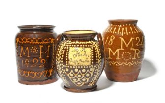 Three large slipware jars, 19th century, one decorated with a panel in cream slip inscribed 'M H