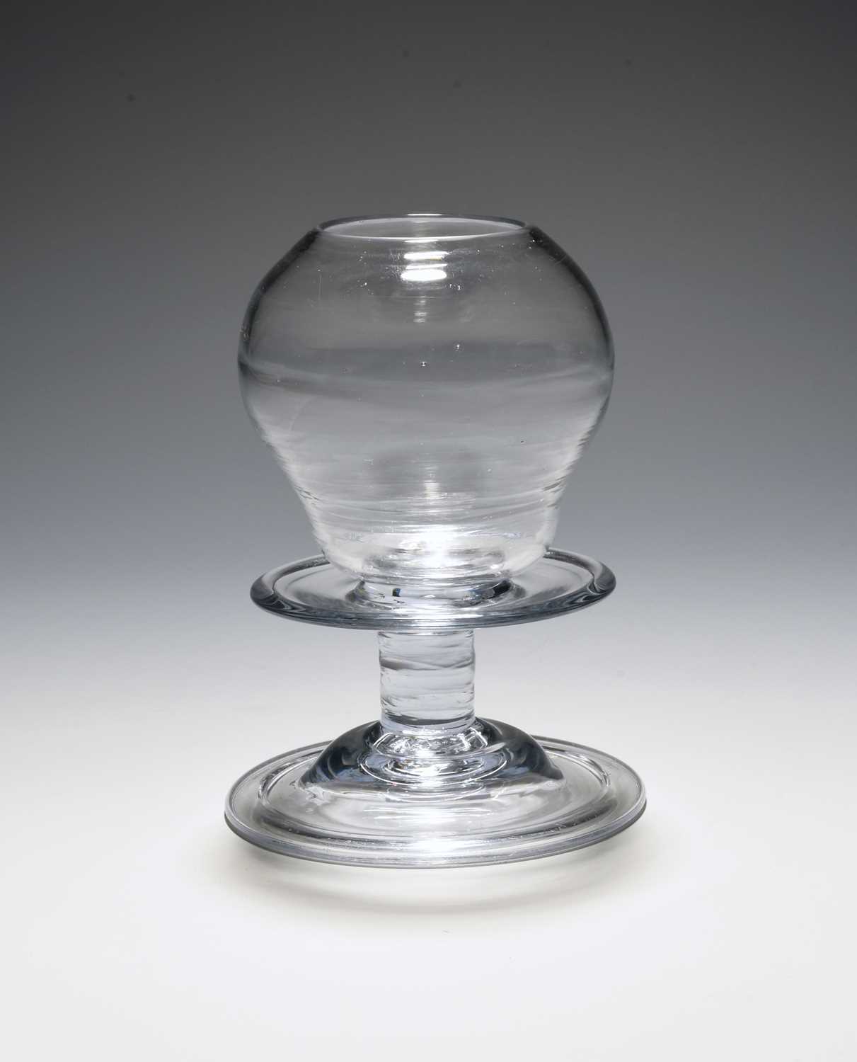A glass lace-maker's lamp, mid 18th century, with an ogee shaped hollow lens over a wide collar,