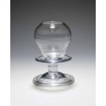 A glass lace-maker's lamp, mid 18th century, with an ogee shaped hollow lens over a wide collar,