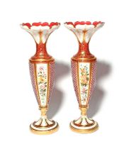 A tall pair of Bohemian glass vases, 19th century, the slender forms overlaid with white over ruby