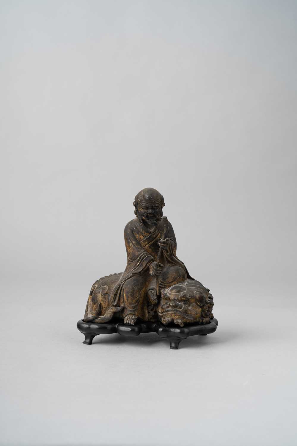 A CHINESE GILT-BRONZE 'LUOHAN AND BUDDHIST LION' GROUP QING DYNASTY The figure seated on the back of