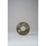 A CHINESE CELADON JADE DISC, BI LATE ZHOU DYNASTY The green mottled disc carved to both sides with a