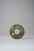 A CHINESE CELADON JADE DISC, BI LATE ZHOU DYNASTY The green mottled disc carved to both sides with a