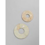 TWO CHINESE GLASS DISCS, BI HAN DYNASTY The smaller with a buff/off-white opaque surface,
