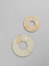 TWO CHINESE GLASS DISCS, BI HAN DYNASTY The smaller with a buff/off-white opaque surface,