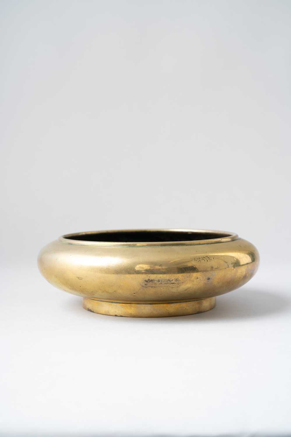 A CHINESE BRONZE INCENSE BURNER QING DYNASTY With a compressed circular body and a raised rim,